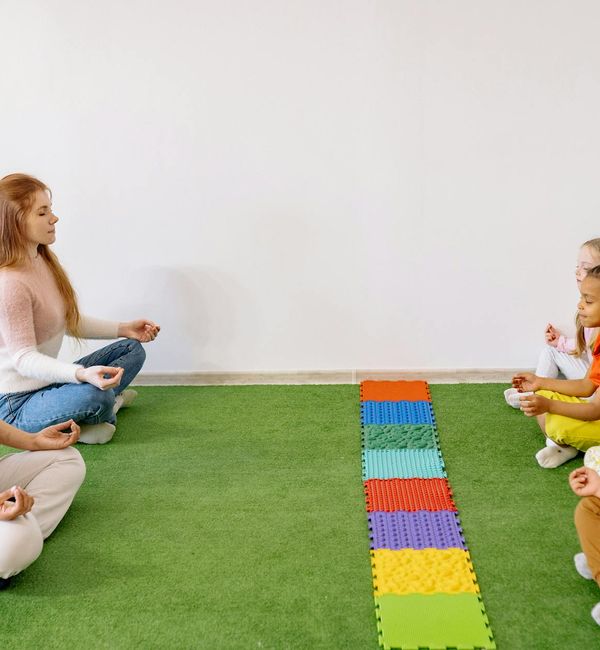 Group of diverse children learning yoga poses playfully from an instructor.